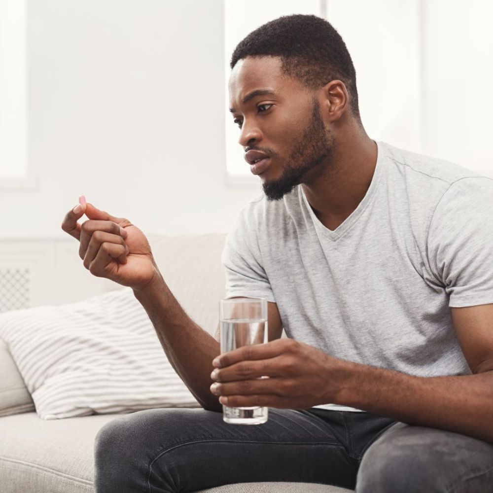 Serious man ready to take a pill sitting on couch