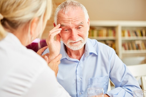 Senior with dementia or Alzheimers is comforted by caring female doctor