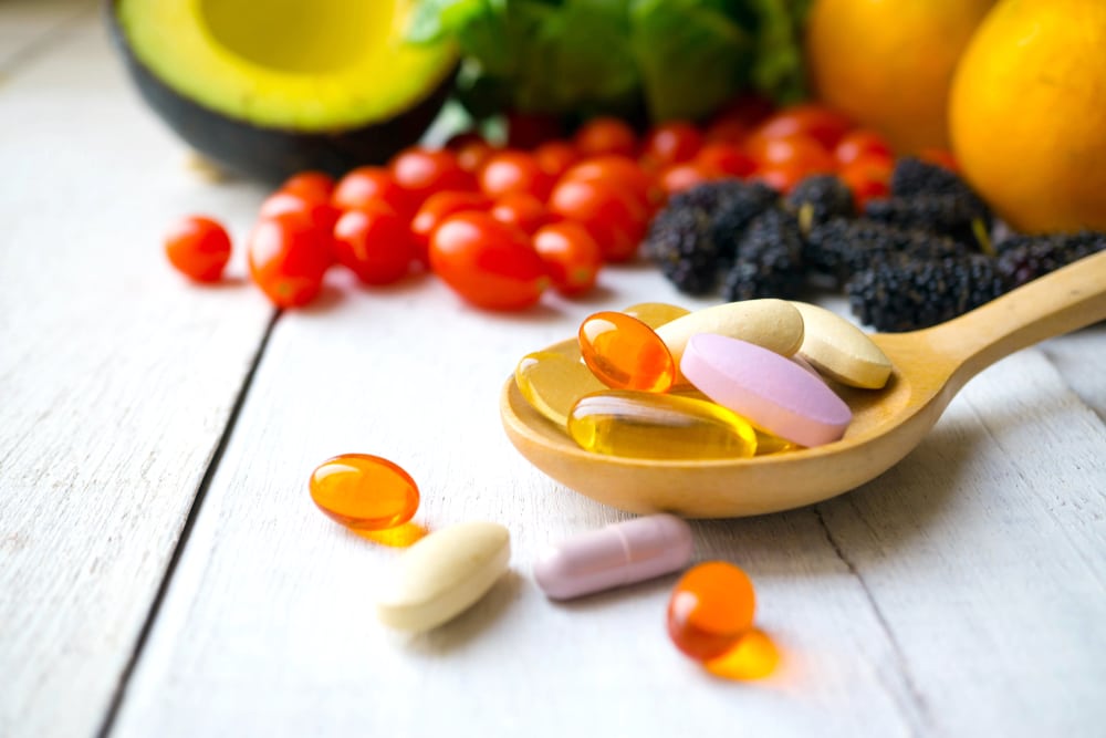 Wooden spoon holding multivitamins and other supplements